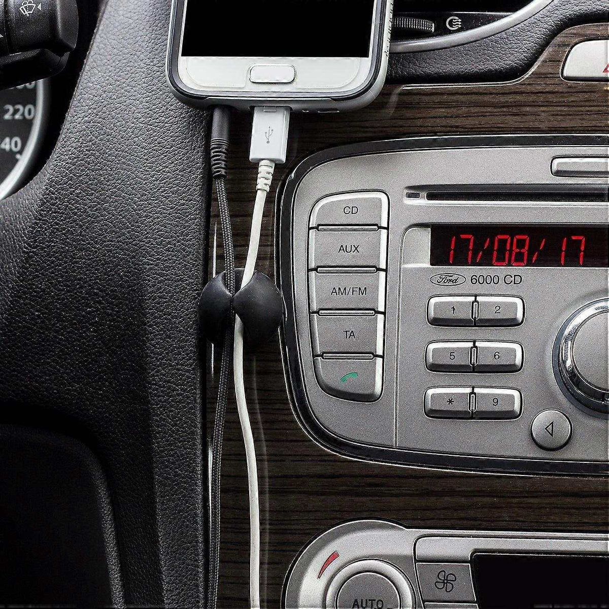 10pcs Black Cable Clamps with smooth black self-adhesive clips holding phone charging cables beside a car stereo