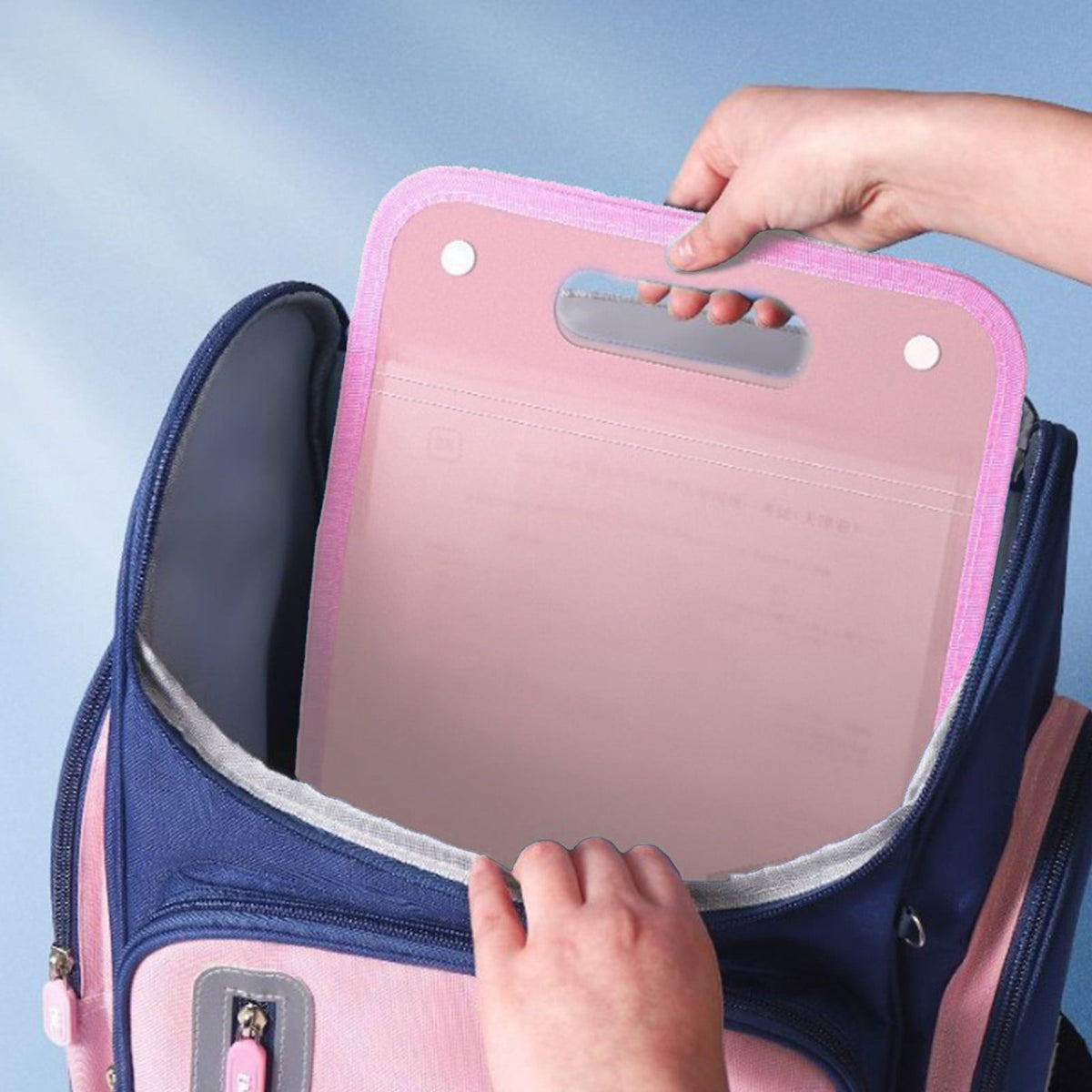 13 Pocket Expanding File Organiser in pink plastic with a built-in carry handle, being placed into a backpack