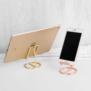 2-Pack Black Universal Aluminum Phone Stand keyword conflicts with the image: two open-frame metal stands in gold and rose gold hold a tablet and phone.