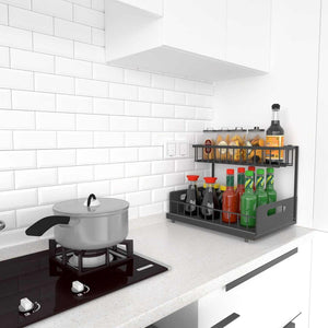 2-Tier Under-Sink Organiser in black metal with two sliding baskets, shown holding bottles and jars