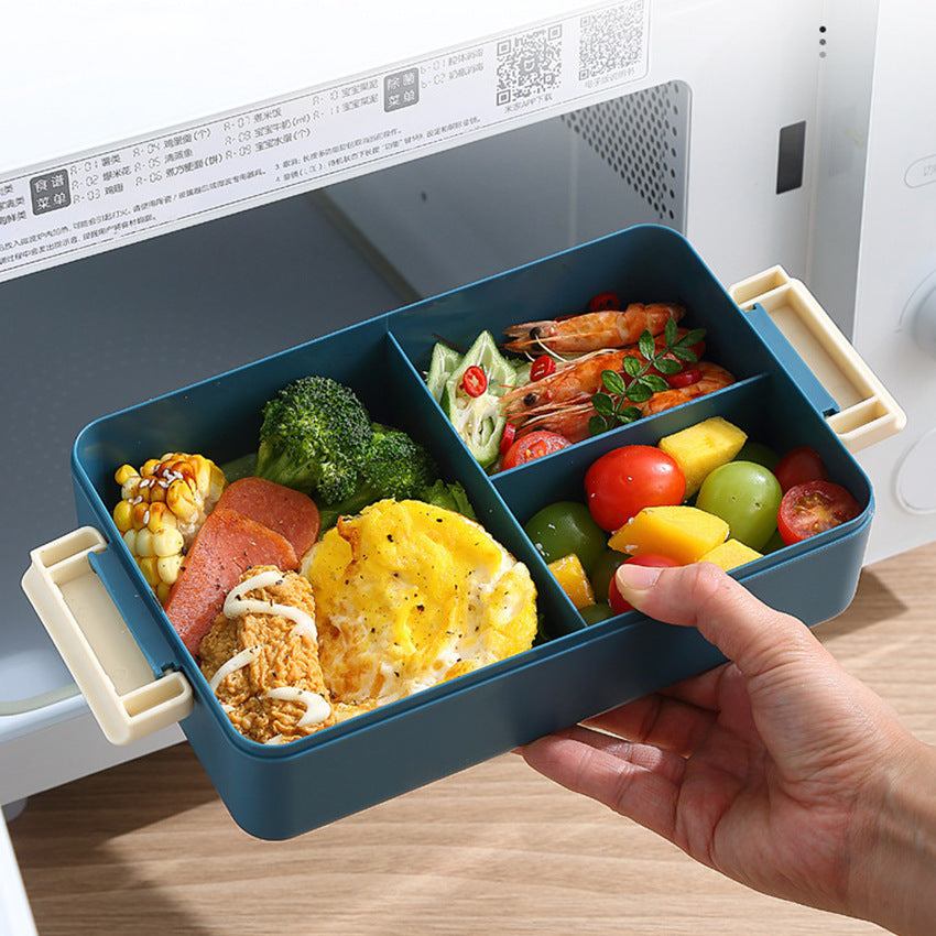2L Double-Layer Bento Lunch Box in dark teal plastic with cream handles and divided compartments, filled with varied foods
