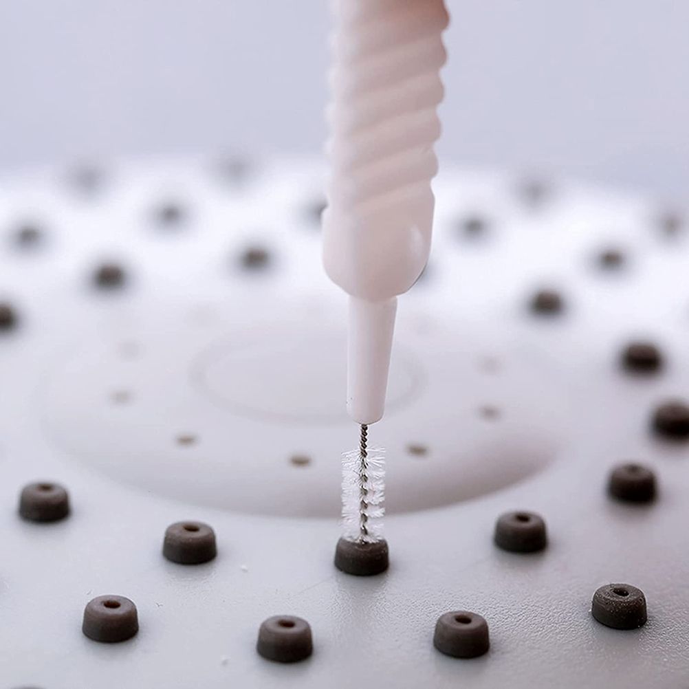 30Pcs Shower Nozzle Cleaning Brush with a white ribbed plastic handle and fine metal bristles cleaning a dark nozzle