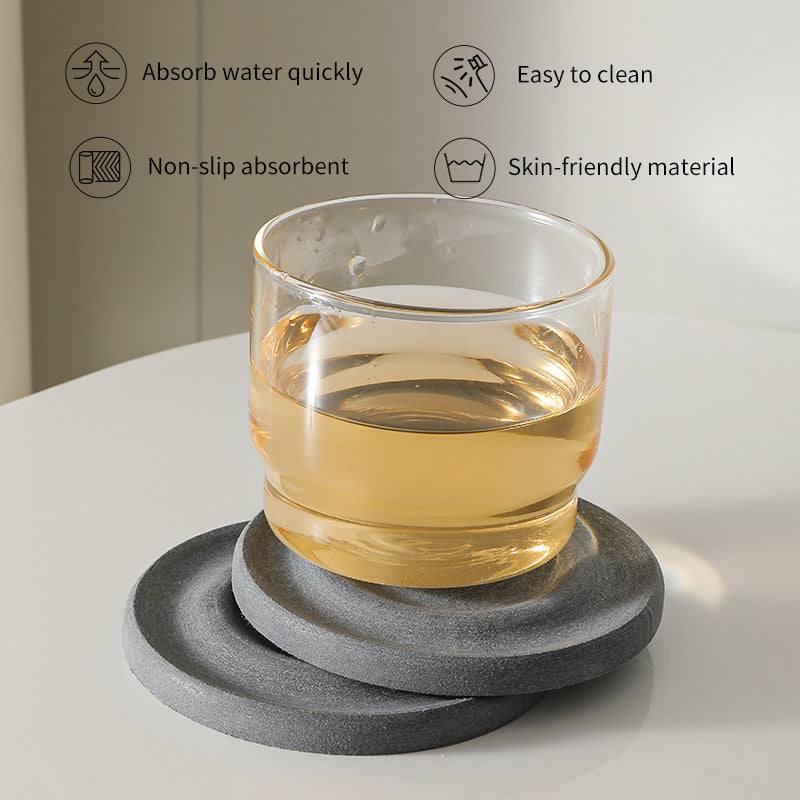 6-Pack Dark Grey Instant Dry diatomite coasters with a charcoal stone texture, shown stacked beneath a glass of tea