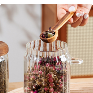 600ml Premium Borosilicate Glass jar with a clear ribbed body, side handle and matching wooden spoon scooping dried rosebuds