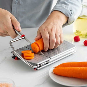 stainless steel cheese slicer with a grey measurement-grid board, metal cutting wire, and red anti-slip feet slicing carrots