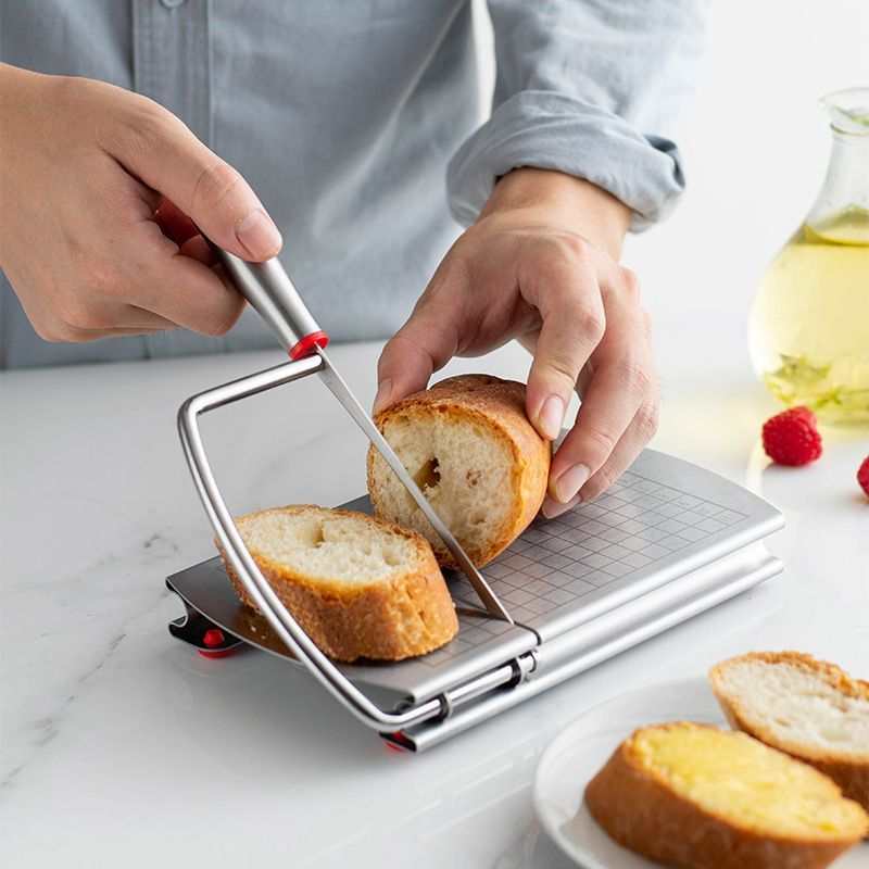 stainless steel cheese slicer with grey gridded board, metal cutting wire, red anti-slip feet, slicing crusty bread