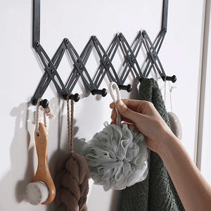 Over Door Hooks in black metal with an expandable scissor-style frame and multiple rounded pegs holding bath accessories