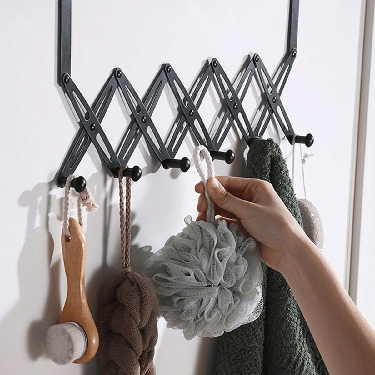 Over Door Hooks in black metal with an expandable scissor-style frame and multiple rounded pegs holding bath accessories