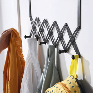 Over Door Hooks rack in black metal with an expandable accordion frame and multiple pegs holding colourful clothing and a bag