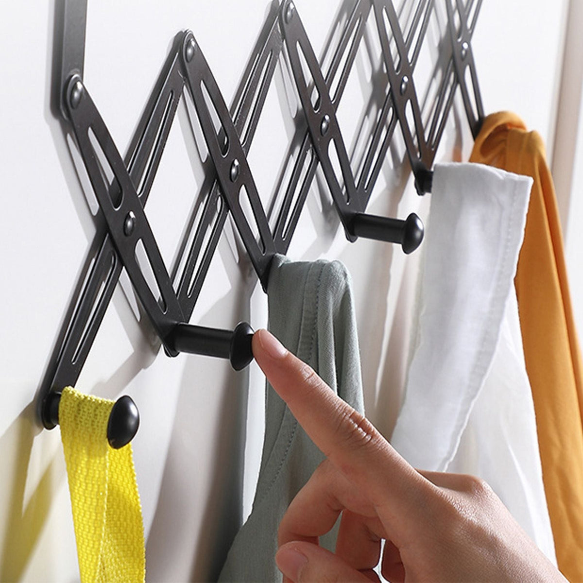 Over Door Hooks rack in black metal with an expandable scissor-style frame and rounded hooks holding towels