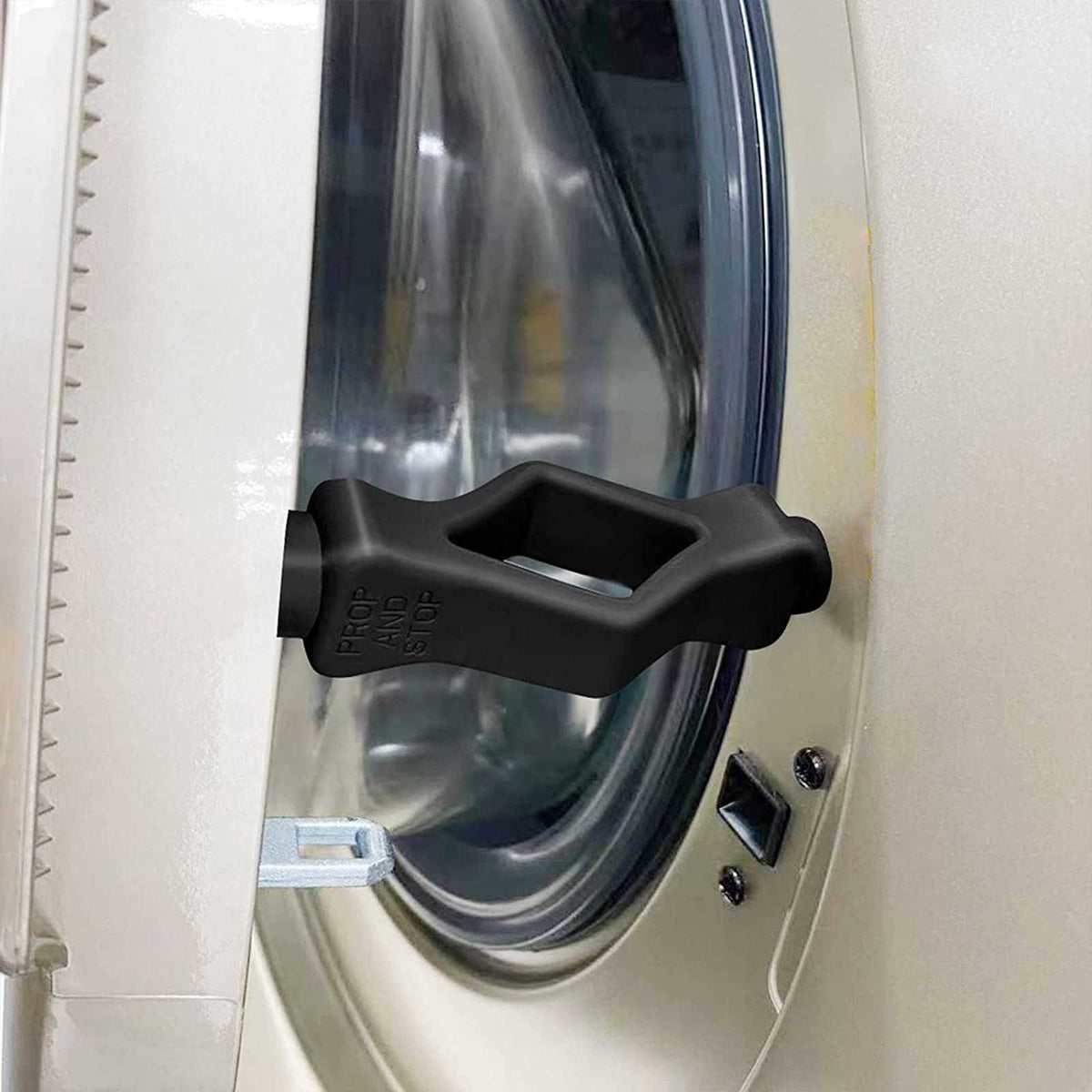Front Load Washer Door Prop in black molded plastic with a wide handle shape, holding a washing machine door ajar
