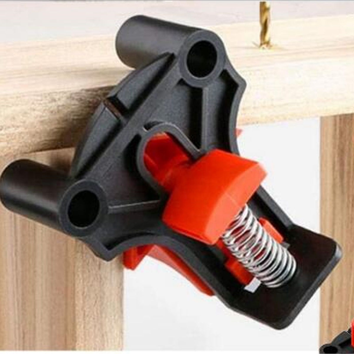 Angle Clamps in black and red ABS with a visible metal spring grip wooden pieces at a corner joint