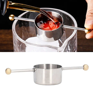 Stainless Steel Measuring Cup with polished metal finish, cylindrical jigger bowl and long double ball handle shown measuring a drink