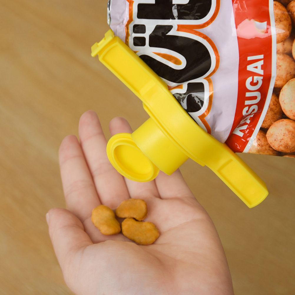 Random Food Bag sealing clip in bright yellow polypropylene attached to a snack packet, with a hinged pouring nozzle