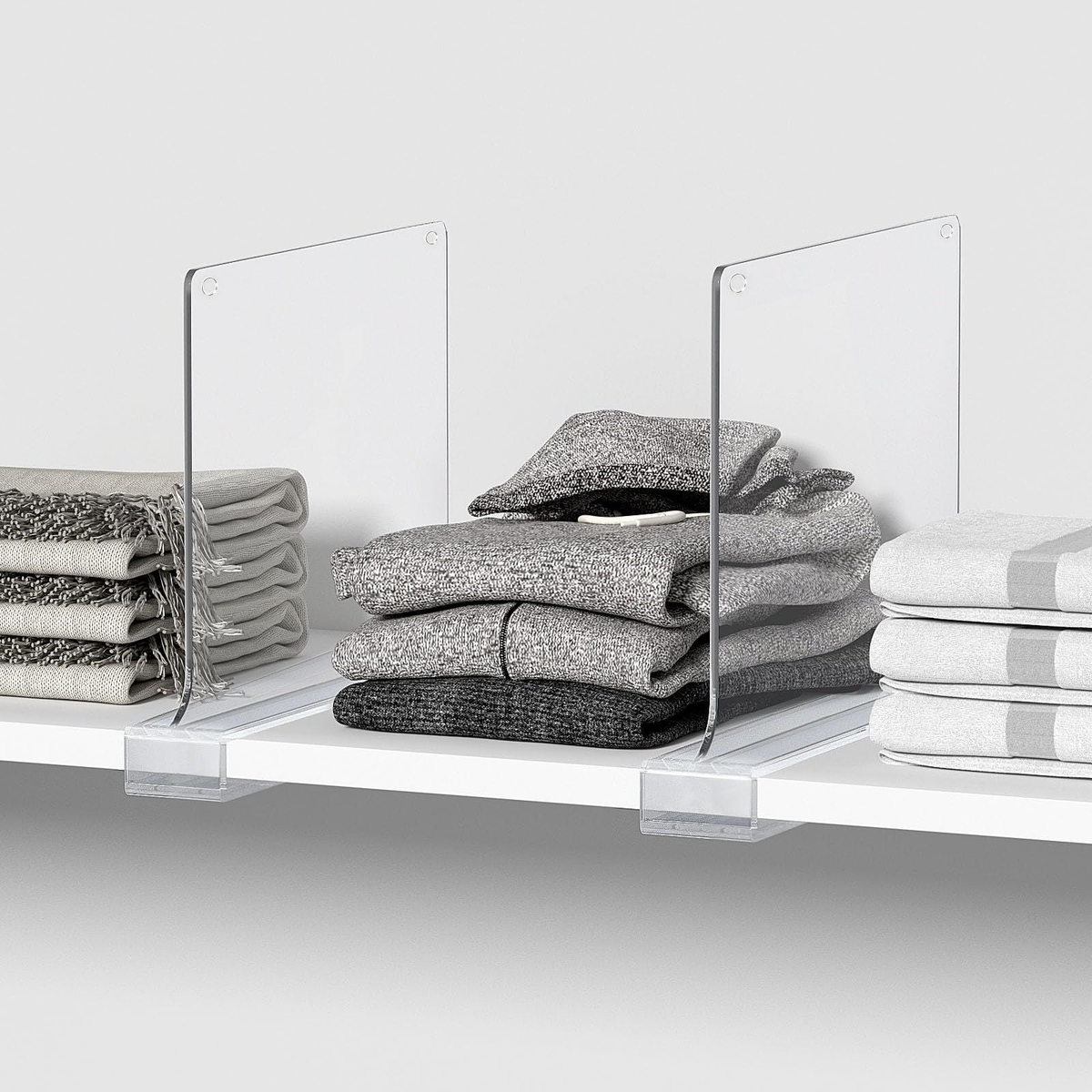 Shelf Dividers for Closet in clear acrylic, clip-on panels separating neatly stacked gray, white and patterned linens.