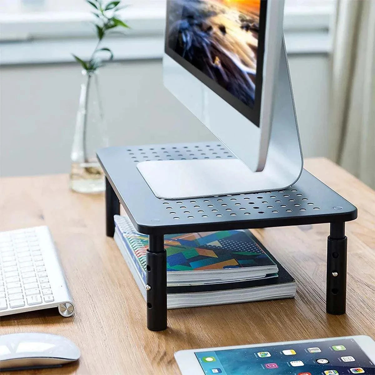Adjustable Monitor & Laptop Riser in black iron with perforated top and three height settings supporting a desktop computer.
