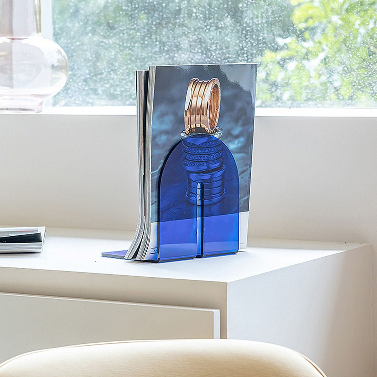 Acrylic Book End in translucent blue acrylic, with a thick glossy L-shaped design supporting a single upright book.