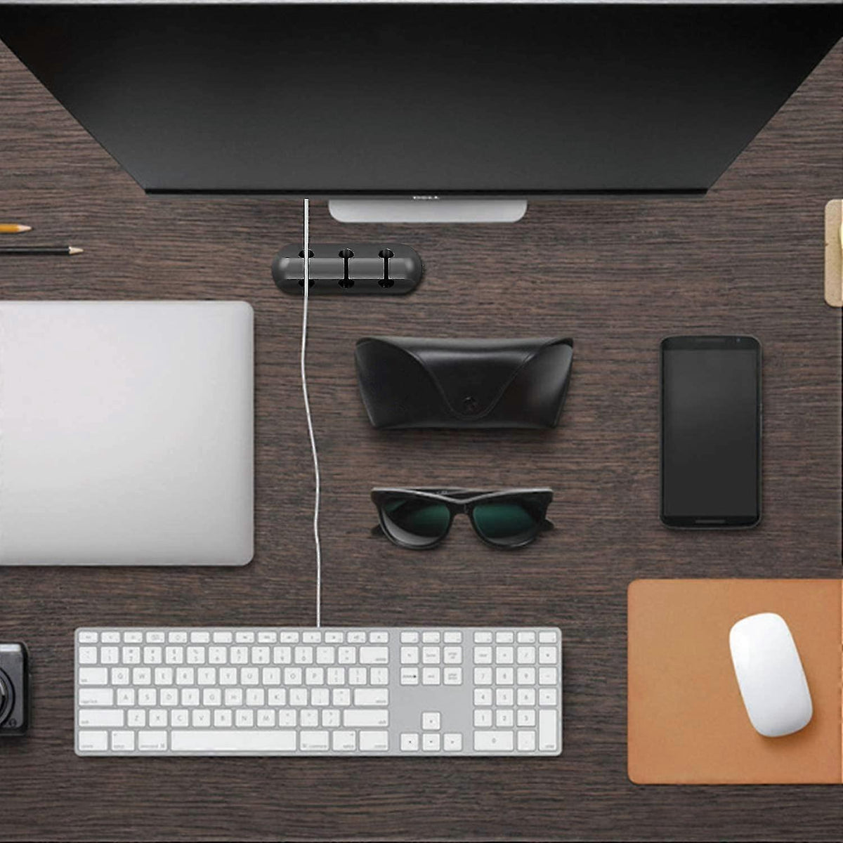 Adhesive Cable Clips in black silicone, holding charging cords neatly beneath a monitor on a desk