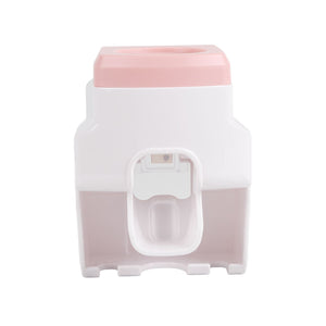 Automatic Toothpaste Dispenser in pink and white plastic, with a central push lever and integrated toothbrush holder slots