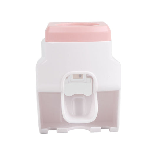 Automatic Toothpaste Dispenser in pink and white plastic, with a central push lever and integrated toothbrush holder slots
