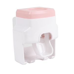 Automatic Toothpaste Dispenser in white and pale pink plastic, with a wall-mounted housing and integrated toothbrush holder