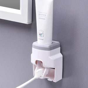 Automatic Toothpaste Dispenser with a white plastic wall-mounted housing, grey top trim and integrated toothbrush holder