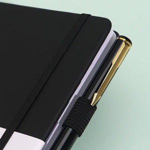 Black Address Book with a smooth black hardcover, elastic closure band and ribbed pen loop holding a black and gold pen