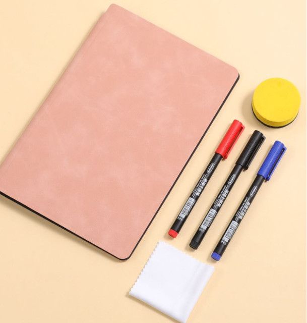 Reusable whiteboard notebook with a smooth pale pink cover and black edging, beside three coloured markers and a yellow eraser; Blue A4 PU Leather