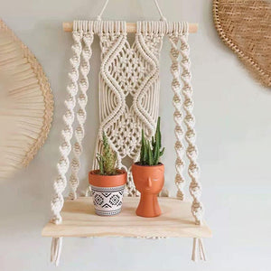 Boho Macrame Wall Hanging Shelf with cream cotton rope, intricate knotted pattern, and a pale wood shelf holding two plants