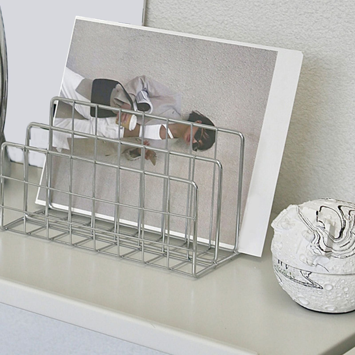 Book Sorter File Magazine rack in silver metal wire, with a rectangular grid design holding a large book upright