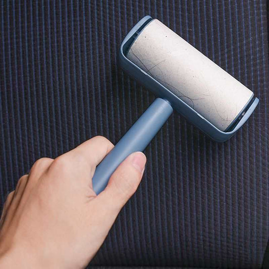 Capsule Sticky Lint Roller with a blue plastic handle and protective shell, showing a white adhesive roll against dark striped fabric.