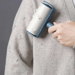 Capsule Sticky Lint Roller with a blue plastic handle and case, removing lint and fuzz from a grey knitted sweater