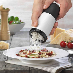Cheese Shredder Rotary with a white and black handheld body dispensing shredded cheese over pasta