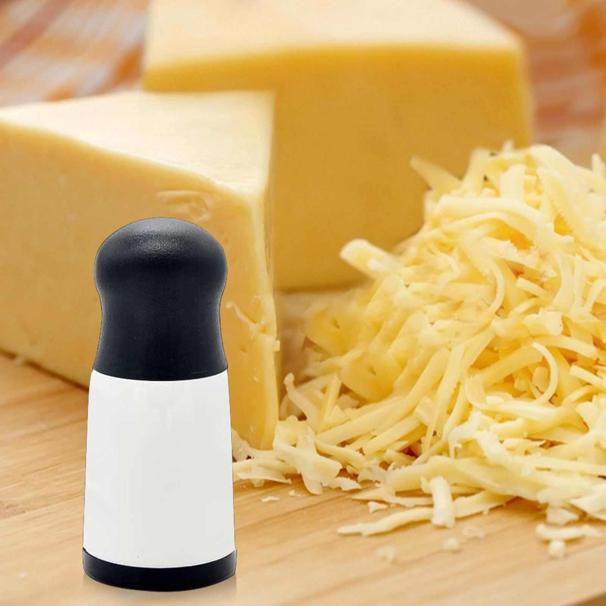 Cheese Shredder Rotary with a white handheld body, black top and base, beside shredded cheese and cheese blocks