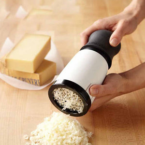 Cheese Shredder Rotary with a white body, black handle and rim, and stainless steel drum grating pale cheese