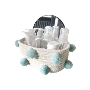 Cotton Rope Knitting storage basket in cream woven cotton with pale blue pom-pom accents, holding toiletry bottles