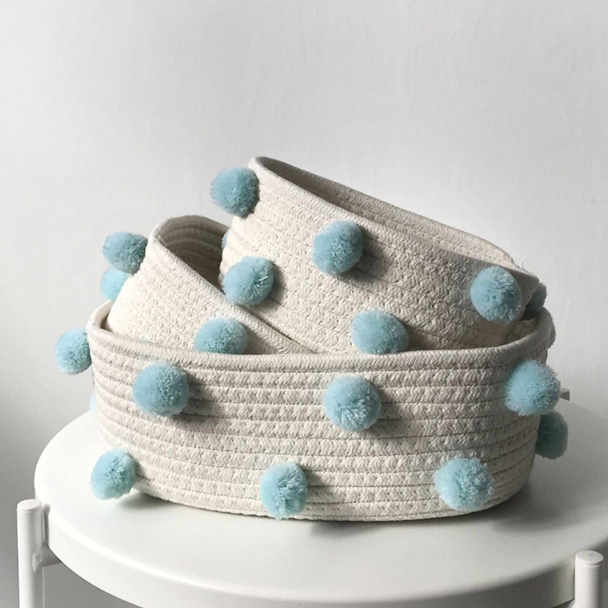 Cotton Rope Knitting storage baskets in cream woven cotton with pale blue pom-pom accents, nested in three sizes