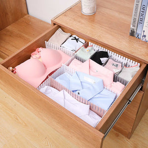 Drawer Divider Organizer with white adjustable plastic partitions separating folded lingerie and clothing in a wooden drawer