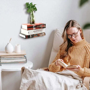 Floating Bookshelf Invisible black metal book holder supports a stack of books and a glass vase, creating a floating display