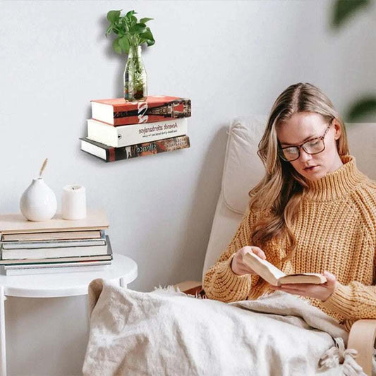 Floating Bookshelf Invisible black metal book holder supports a stack of books and a glass vase, creating a floating display