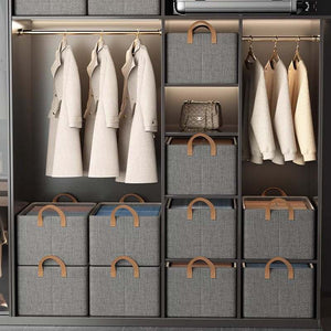 Foldable Fabric Storage Bin with grey woven fabric, brown leather-look handles and a structured rectangular shape