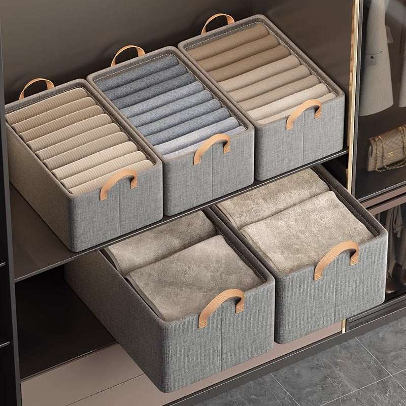Foldable Fabric Storage Bin in grey woven fabric with tan handles, holding neatly arranged clothing in closet shelving