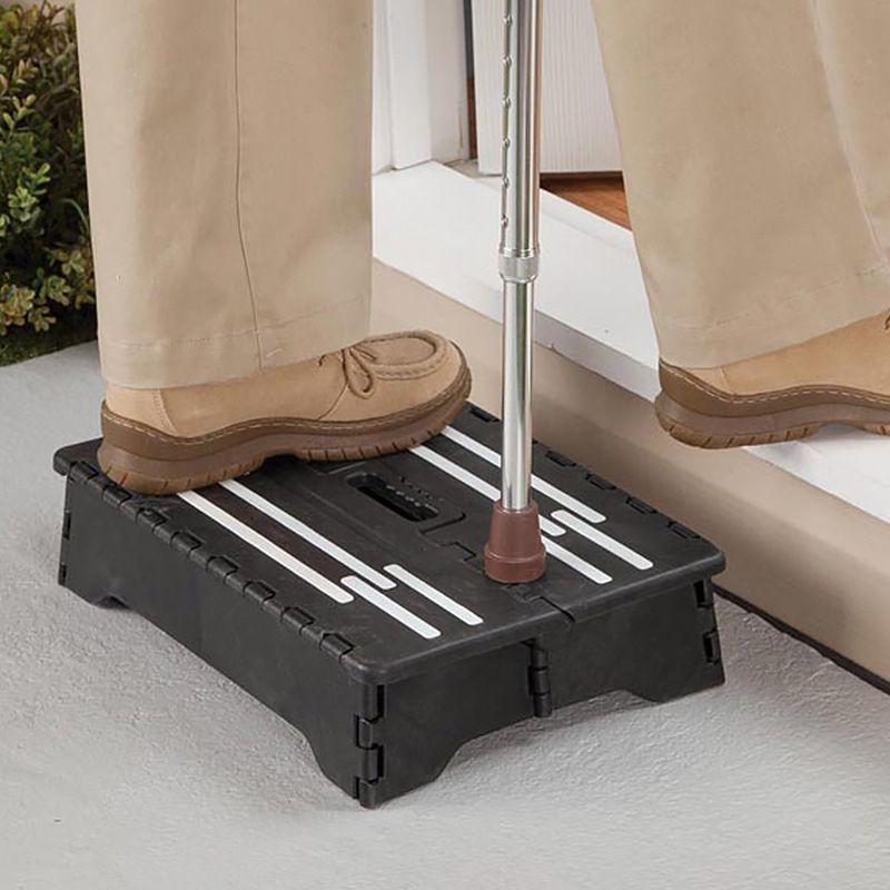 Folding Step Stool in black plastic with white anti-slip strips, supporting a person standing with a cane