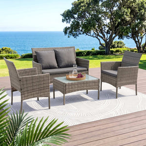 Gardeon 4-Piece Outdoor Sofa Set in grey woven rattan with dark grey cushions, two pillows and a glass-top coffee table