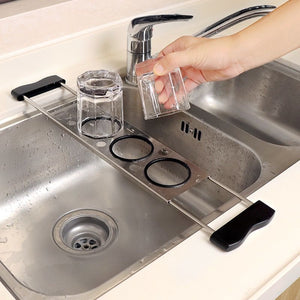 Heavy-Duty Stainless Steel Kitchen sink caddy in silver metal with two black-rimmed cup holders and a sliding bridge design