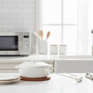 Hot Plate Gripper Tongs with a white silicone grip and metal arms clasp a white lidded ceramic pot