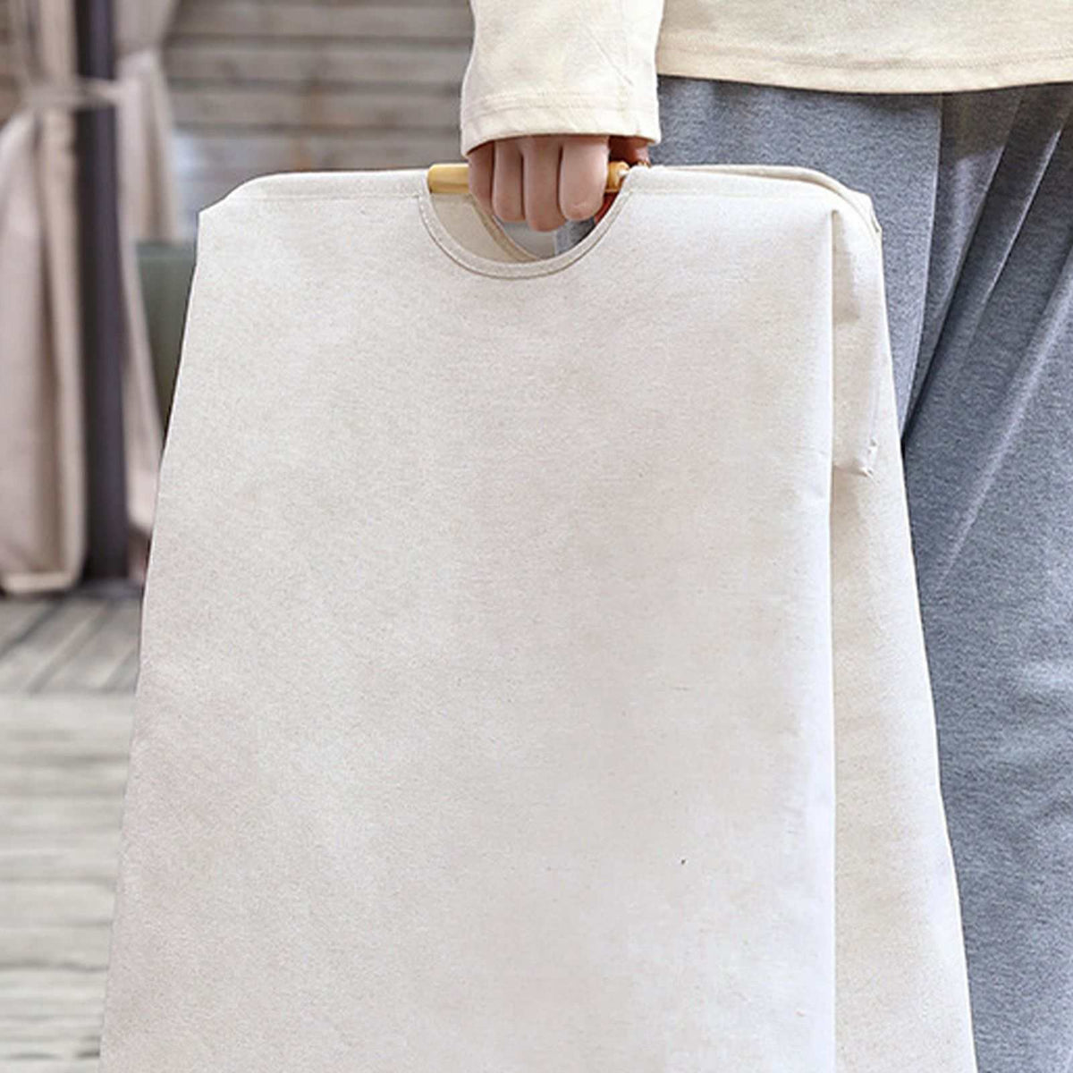 Laundry Basket Waterproof in cream cotton-linen fabric, with a flat collapsible shape and a wooden carry handle.