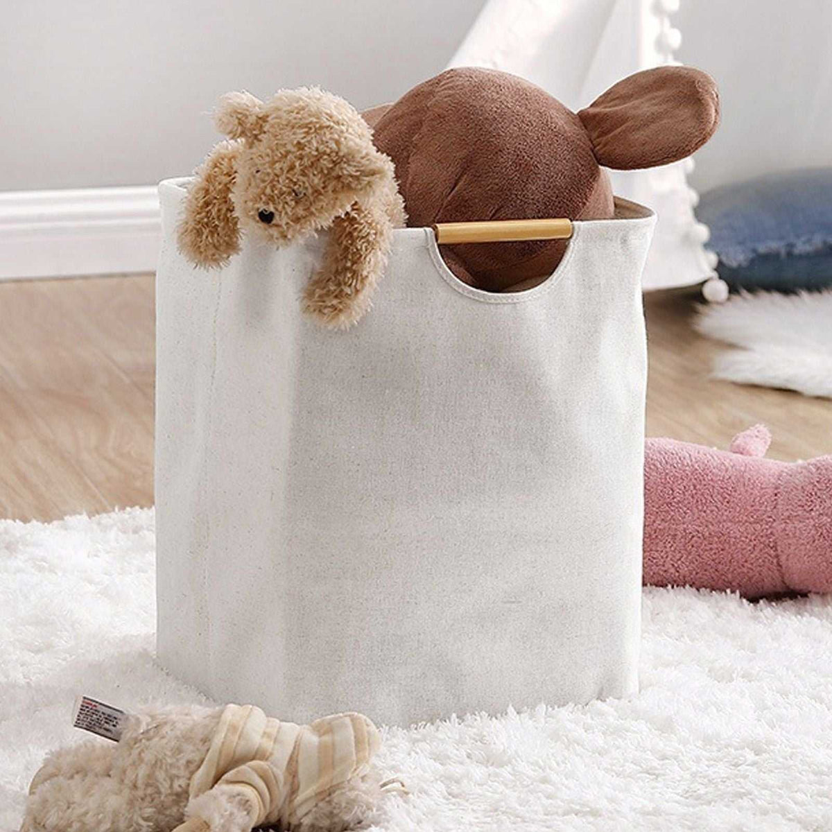 Laundry Basket Waterproof hamper in natural cream fabric with a wooden handle, holding plush toys and soft linens