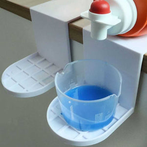 Laundry Detergent Holder with white plastic drip-catching trays and a translucent blue measuring cup beneath a detergent spout