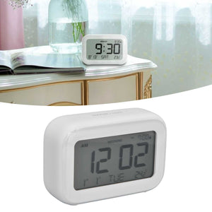 Mini Digital Alarm Clock in smooth white plastic with a rounded rectangular body and large grey LCD display showing time, date and alarm indicators.